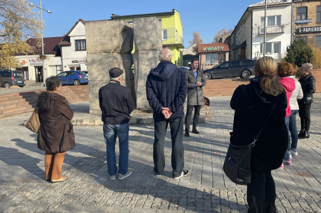 Spacer historyczny w 79 rocznicę likwidacji getta w Starachowicach-Wierzbniku - grupa spacerowiczów przed pomnikiem getta na Rynku.